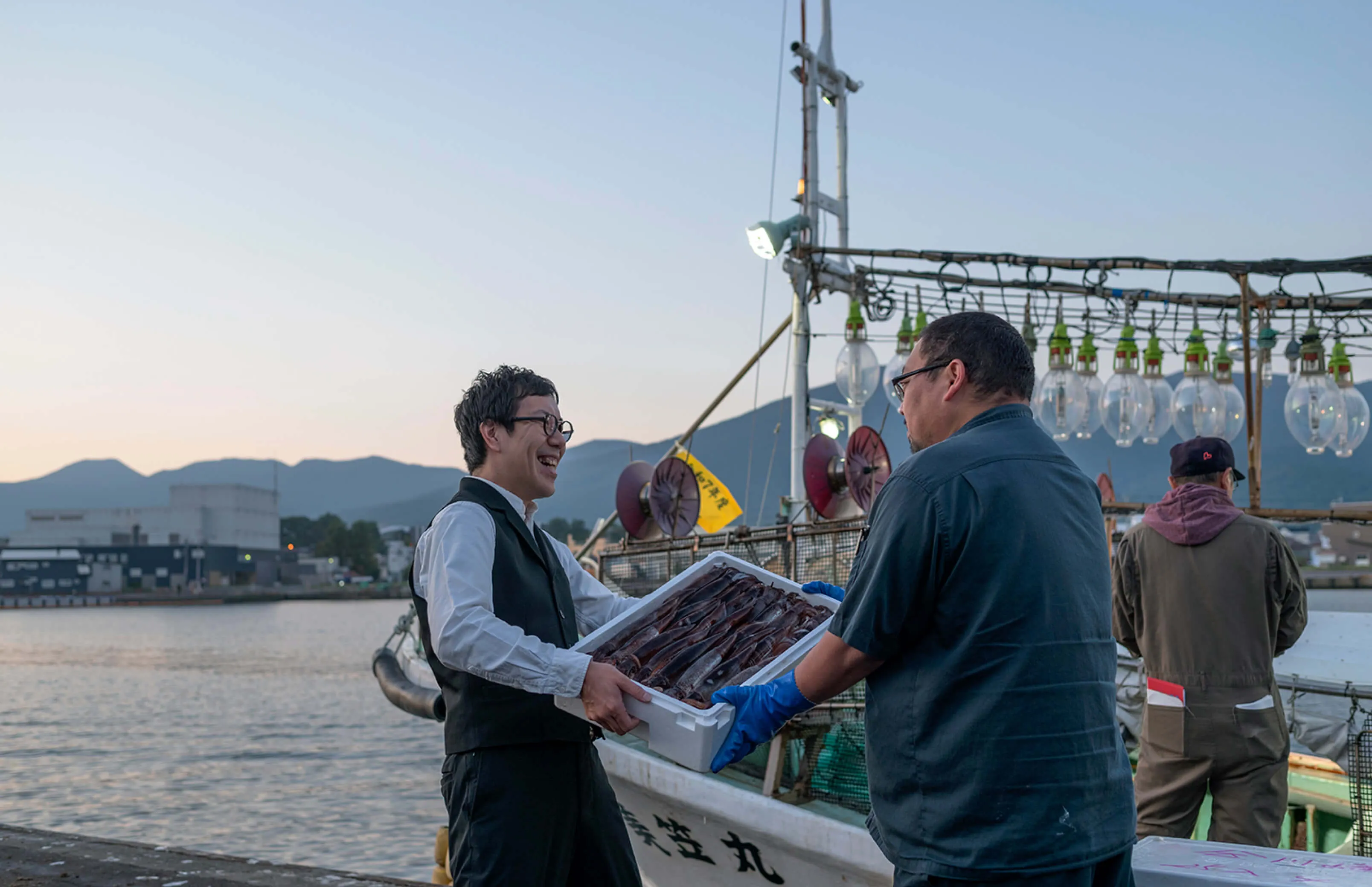 漁船の前で海鮮の仕入れをしている様子